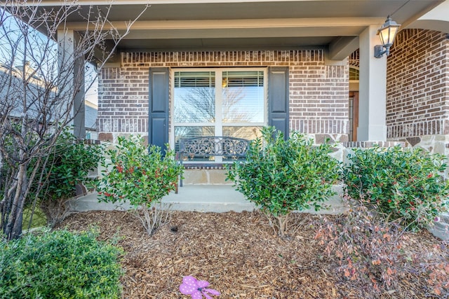 entrance to property with brick siding and a porch