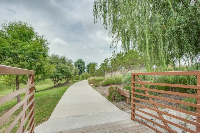 view of property's community featuring a lawn and fence