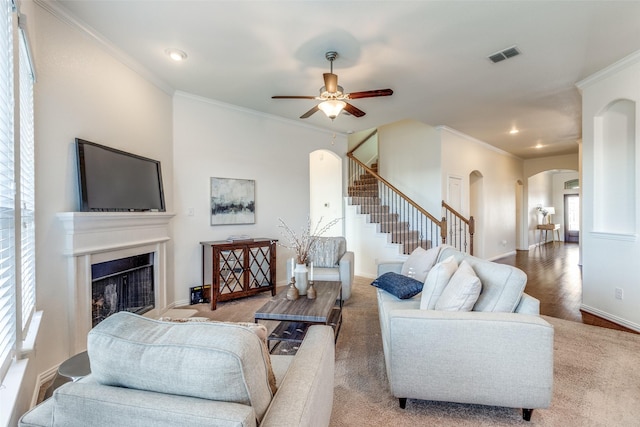 living room featuring stairway, arched walkways, ornamental molding, and a fireplace