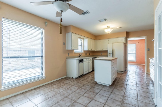 kitchen with a sink, white refrigerator with ice dispenser, light countertops, a center island, and a ceiling fan