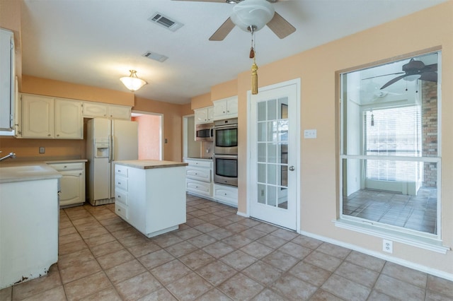kitchen featuring appliances with stainless steel finishes, light countertops, a ceiling fan, a kitchen island, and visible vents