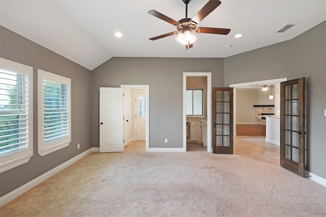 unfurnished bedroom featuring french doors, a fireplace, visible vents, light carpet, and vaulted ceiling