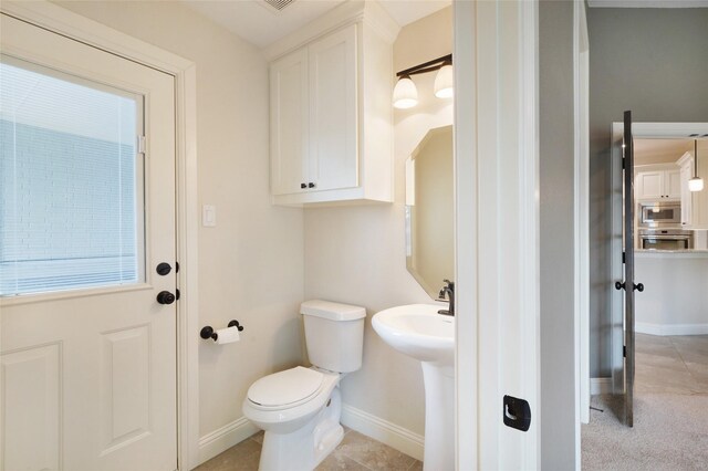 bathroom with toilet, tile patterned flooring, and baseboards