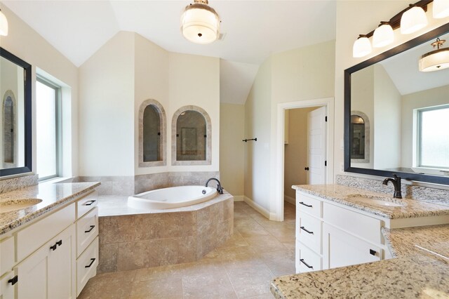 full bath with lofted ceiling, two vanities, a sink, and a bath