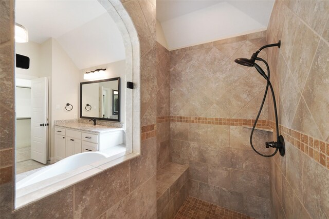 full bath featuring lofted ceiling, a tile shower, and vanity