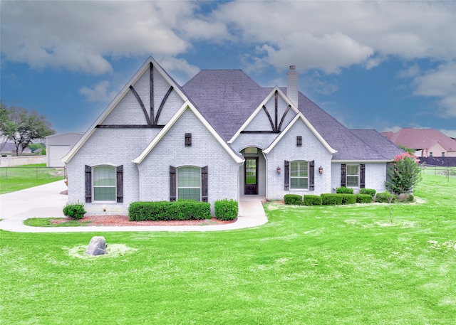 view of front of property with brick siding, a chimney, a front yard, and a shingled roof