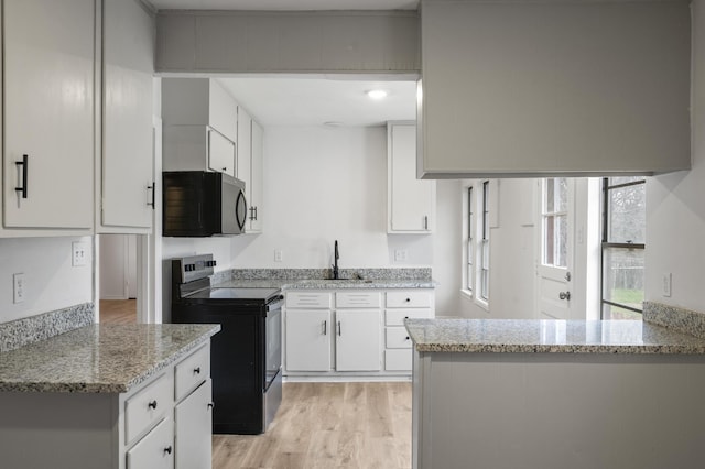 kitchen with electric stove, white cabinets, stainless steel microwave, and light stone countertops