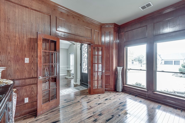 interior space with light wood finished floors, visible vents, wood walls, and arched walkways