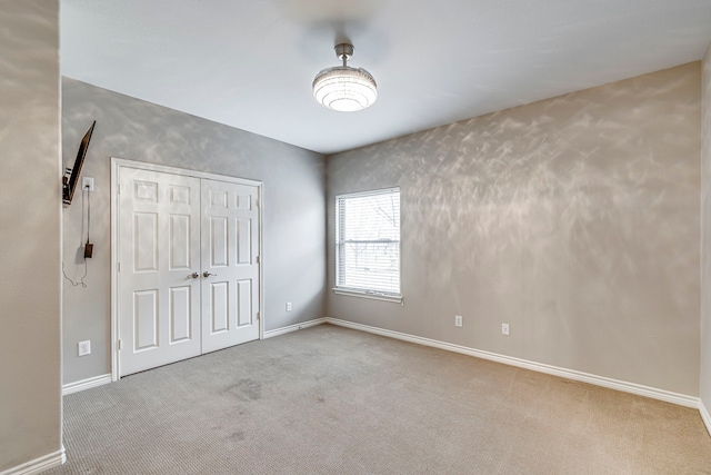 unfurnished bedroom with a closet, carpet flooring, and baseboards