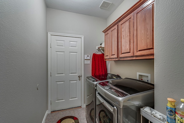 clothes washing area with visible vents, a textured wall, cabinet space, tile patterned floors, and washing machine and dryer