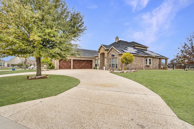 view of front of house with concrete driveway, a front yard, a garage, brick siding, and solar panels