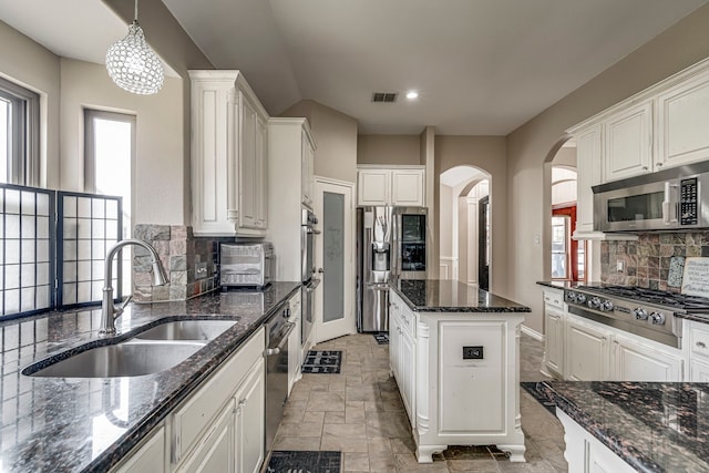 kitchen featuring tasteful backsplash, visible vents, white cabinets, stainless steel appliances, and a sink