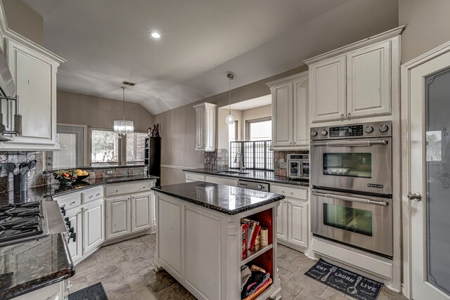 kitchen with lofted ceiling, a sink, stainless steel appliances, white cabinets, and backsplash