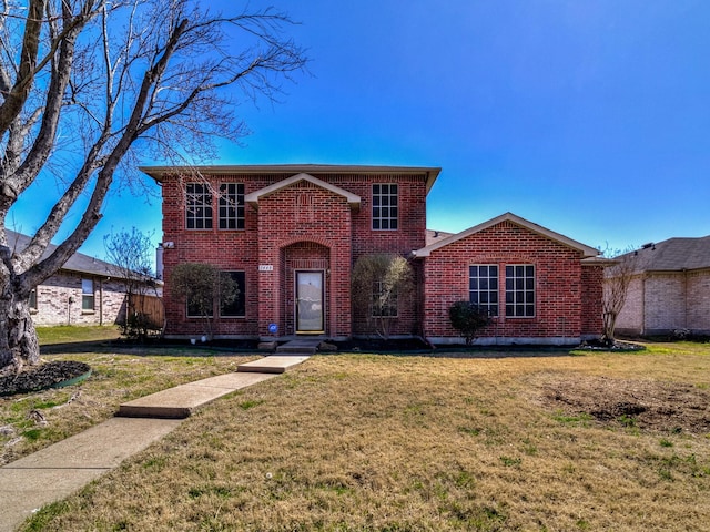 traditional-style house featuring brick siding and a front lawn