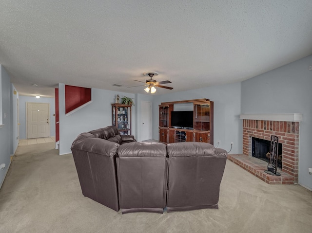 living area with a brick fireplace, a ceiling fan, a textured ceiling, and light colored carpet