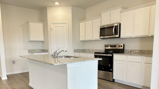 3600 Skylane Ave, Corsicana, TX 75110 - kitchen with appliances with stainless steel finishes, a sink, wood finished floors, a center island with sink, and white cabinetry