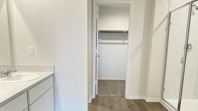 3600 Skylane Ave, Corsicana, TX 75110 - bathroom with wood finished floors, vanity, a spacious closet, baseboards, and a shower stall