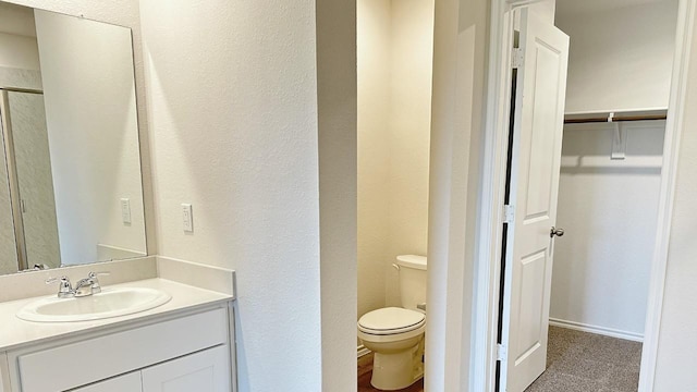 3600 Skylane Ave, Corsicana, TX 75110 - bathroom with toilet, vanity, a textured wall, and a walk in closet