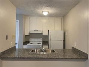 kitchen featuring sink, white cabinets, dark stone counters, kitchen peninsula, and white appliances