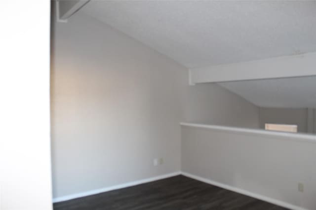 bonus room featuring dark hardwood / wood-style floors and lofted ceiling with beams