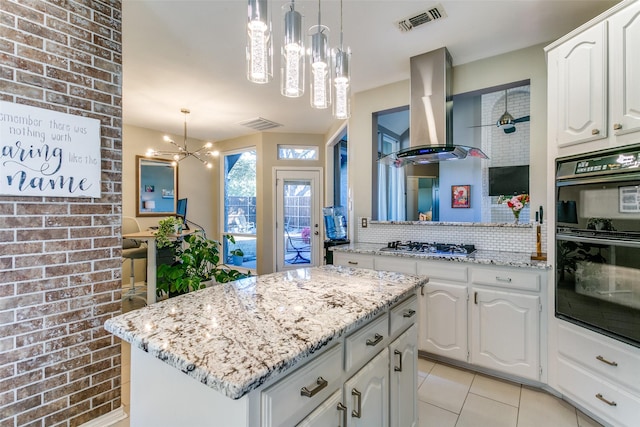 kitchen with extractor fan, dobule oven black, white cabinets, a center island, and decorative light fixtures