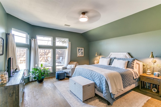 bedroom featuring vaulted ceiling, light wood finished floors, visible vents, and a ceiling fan