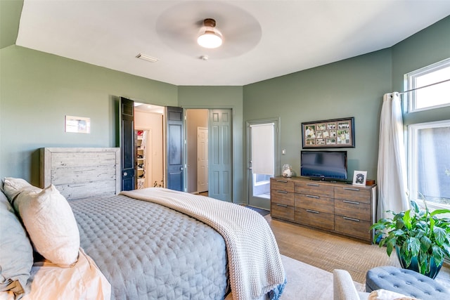 bedroom with visible vents, light colored carpet, ceiling fan, a walk in closet, and a closet