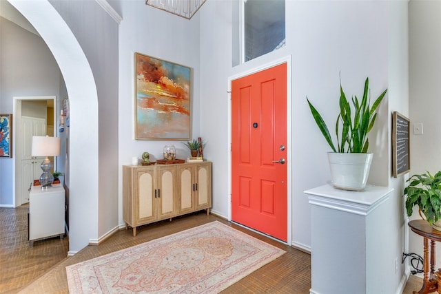 entrance foyer featuring arched walkways, a high ceiling, and baseboards