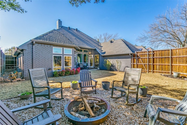 back of house featuring a patio, an outdoor fire pit, brick siding, fence, and a chimney