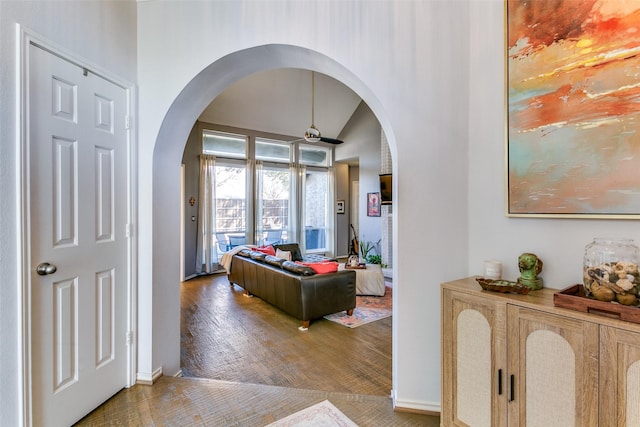 interior space featuring lofted ceiling, ceiling fan, arched walkways, and wood finished floors