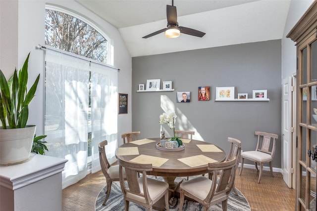 dining area with a ceiling fan, lofted ceiling, and baseboards