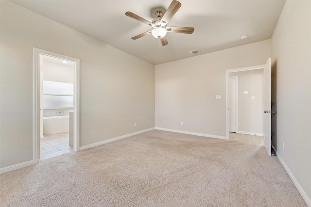 unfurnished bedroom featuring ceiling fan, light colored carpet, and ensuite bath