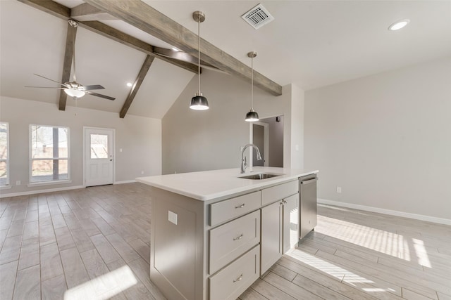 kitchen with sink, vaulted ceiling with beams, hanging light fixtures, a kitchen island with sink, and ceiling fan