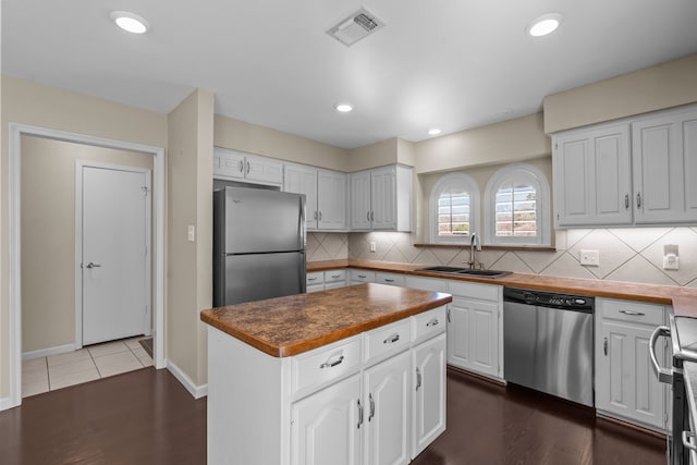 kitchen with visible vents, appliances with stainless steel finishes, white cabinets, and a sink