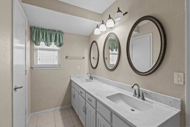 bathroom with baseboards, double vanity, a sink, and tile patterned floors