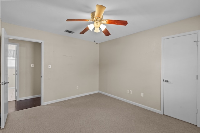 empty room with carpet, visible vents, ceiling fan, and baseboards