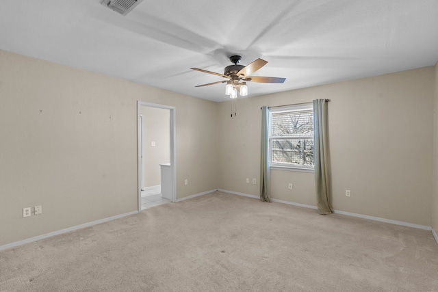 spare room with baseboards, ceiling fan, visible vents, and light colored carpet