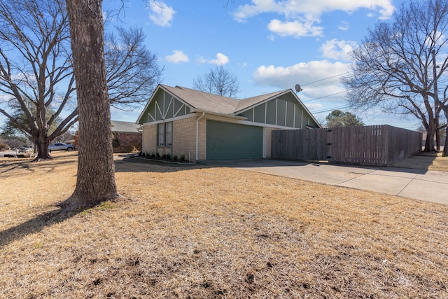 view of side of property with brick siding, concrete driveway, an attached garage, a gate, and fence