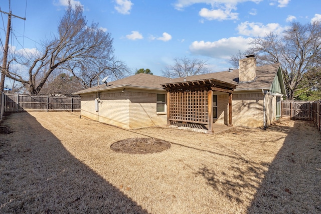 back of property featuring a fenced backyard, a chimney, and brick siding