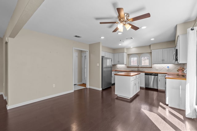 kitchen featuring a sink, appliances with stainless steel finishes, a kitchen island, and butcher block counters