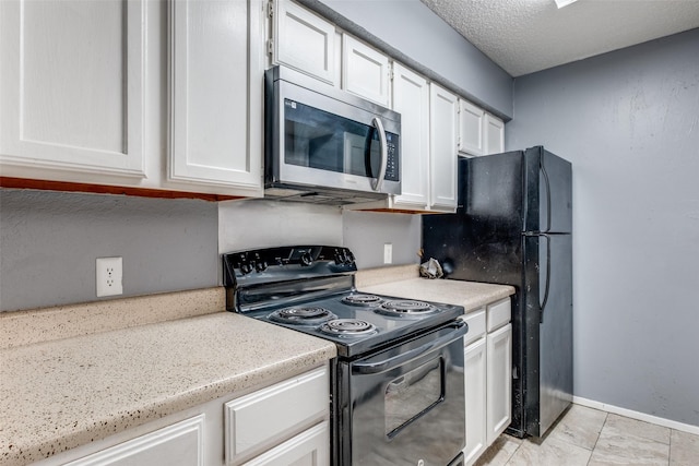 kitchen featuring baseboards, black / electric stove, stainless steel microwave, and white cabinets