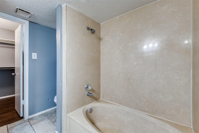 full bathroom featuring a textured ceiling, bathtub / shower combination, toilet, visible vents, and tile patterned floors