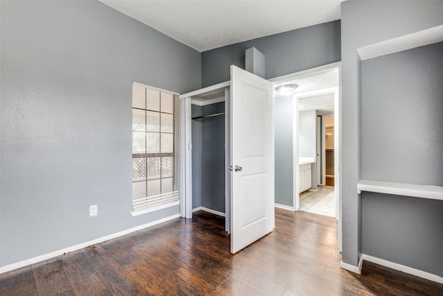 unfurnished bedroom featuring a closet, wood finished floors, and baseboards