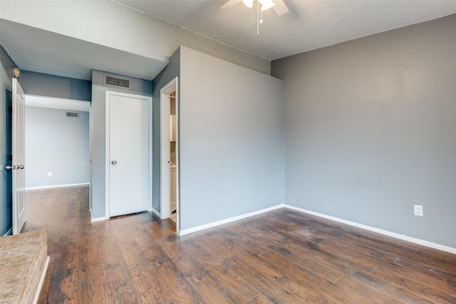 spare room featuring a textured ceiling, dark wood-style flooring, visible vents, and baseboards