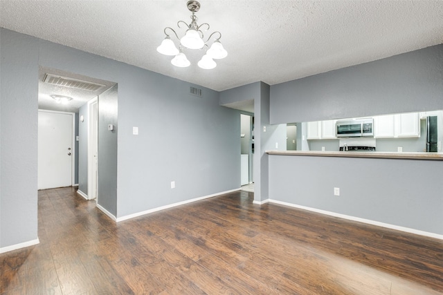 unfurnished living room featuring baseboards, a textured ceiling, visible vents, and dark wood-style flooring