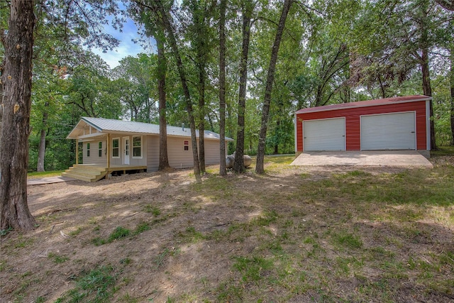 view of front of home featuring a garage, an outbuilding, metal roof, and a porch