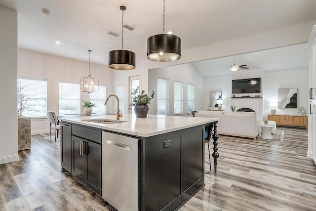 kitchen featuring sink, dishwasher, a kitchen island with sink, plenty of natural light, and decorative light fixtures