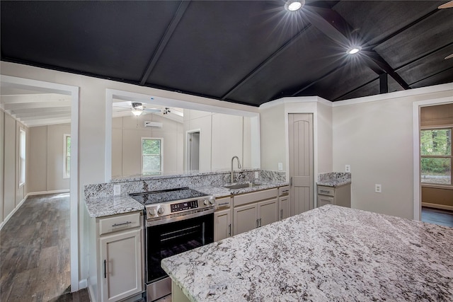 kitchen featuring light stone counters, sink, lofted ceiling with beams, and stainless steel electric range oven