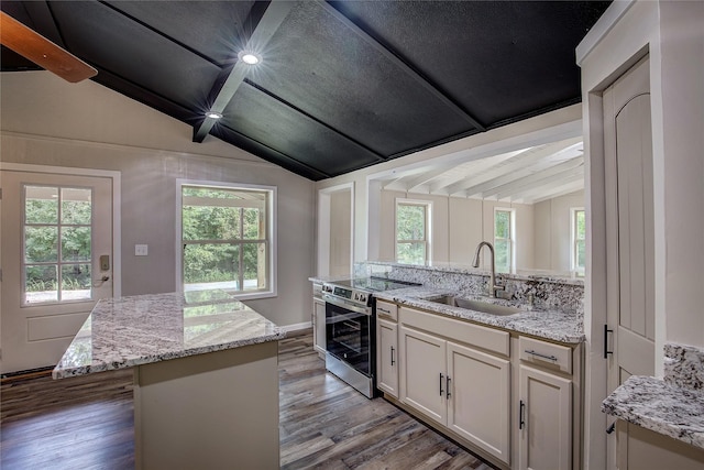 kitchen with sink, stainless steel range with electric stovetop, vaulted ceiling with beams, light stone countertops, and a kitchen island