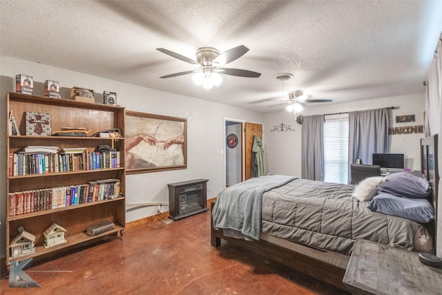 bedroom with ceiling fan, concrete flooring, a textured ceiling, and a wood stove